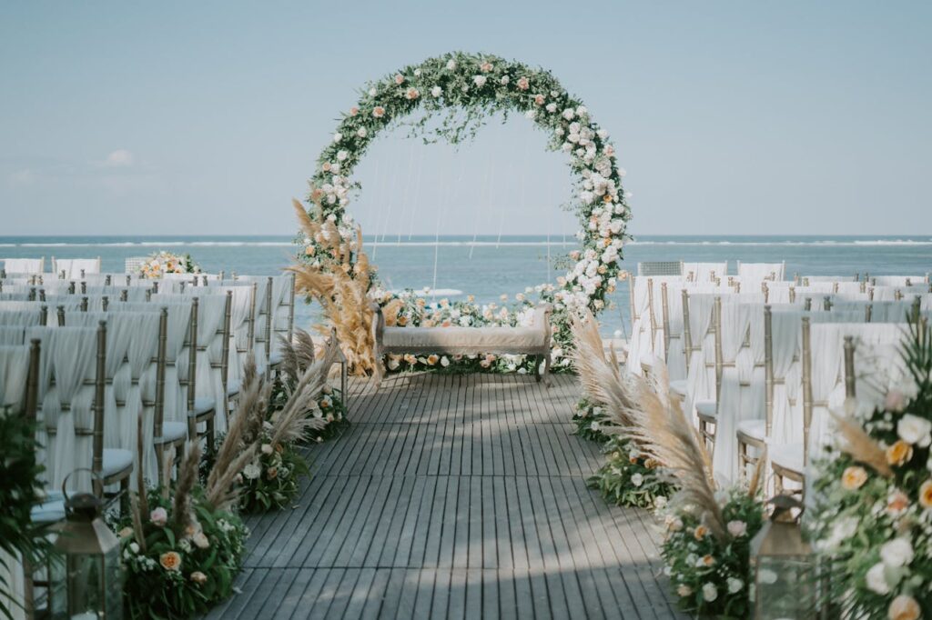 Beautiful beachside wedding setup with elegant floral arch and ocean backdrop.